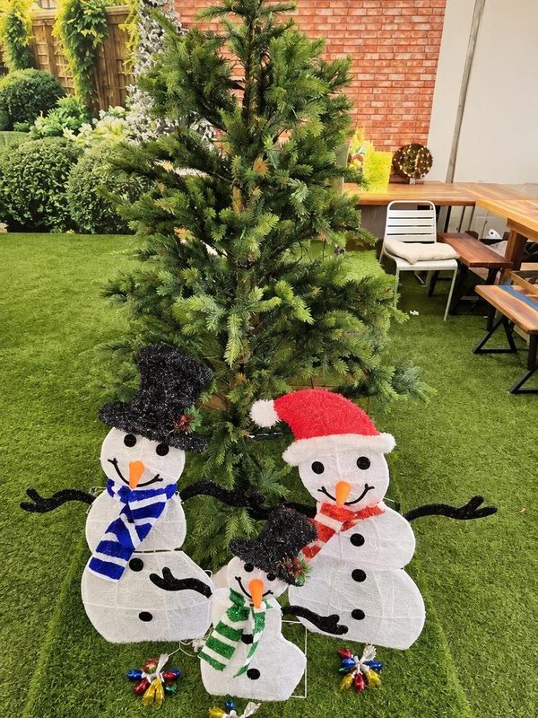 Light-up snowman family in front of a tall tree